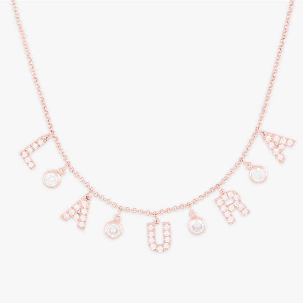 Rose gold personalized letter necklace with cubic zirconia stones spelling "LAURA" and larger zirconia accents.