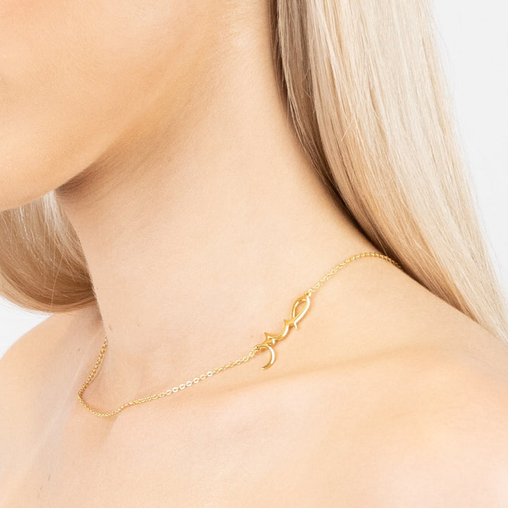 Sabr Hub Arabic Necklace in gold worn around the neck showcasing intricate lettering and minimalist design.