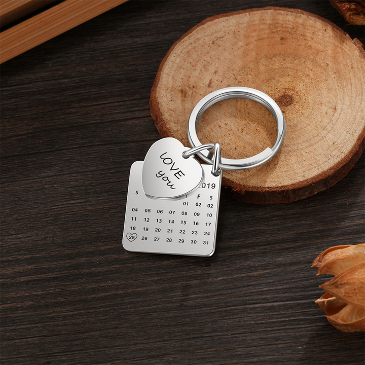 Personalized calendar photo keychain with engraved heart and custom date square pendant keyring on wooden background