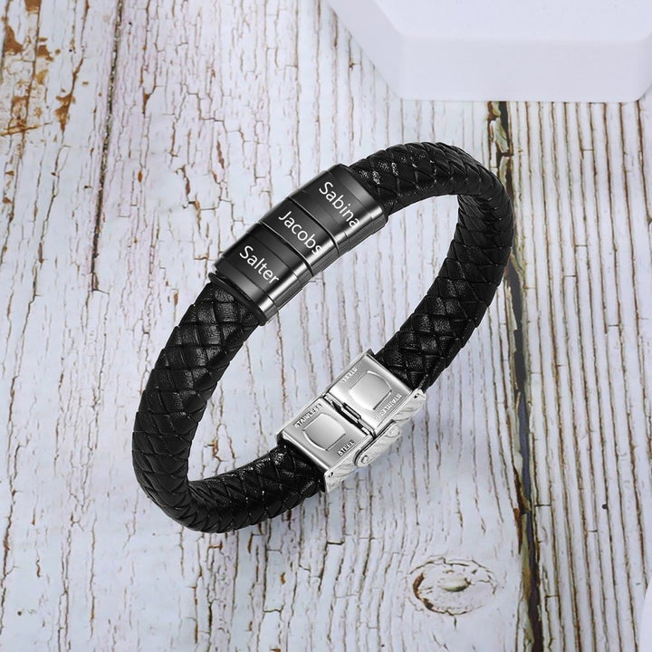 Customizable black faux leather men's bracelet with three stainless steel rings engraved with names Sabina, Jacob, and Salter.