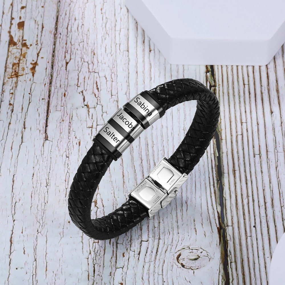 Customizable men's leather bracelet with three engraved rings on a black faux leather strap, personalized with names.