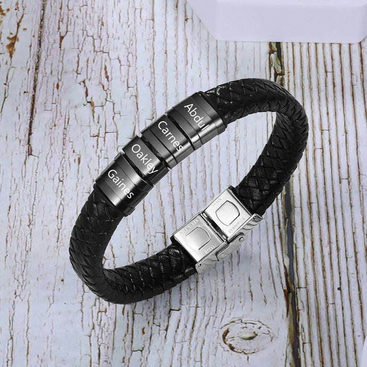 Customizable men's leather bracelet with four engraved stainless steel rings on a black faux leather strap