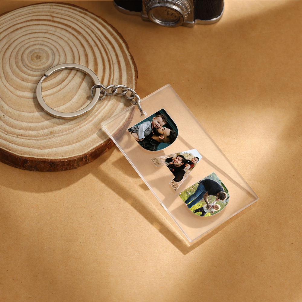 Custom 'DAD' acrylic photo keychain with personalized picture charms for fathers featuring three photos on a wooden background.