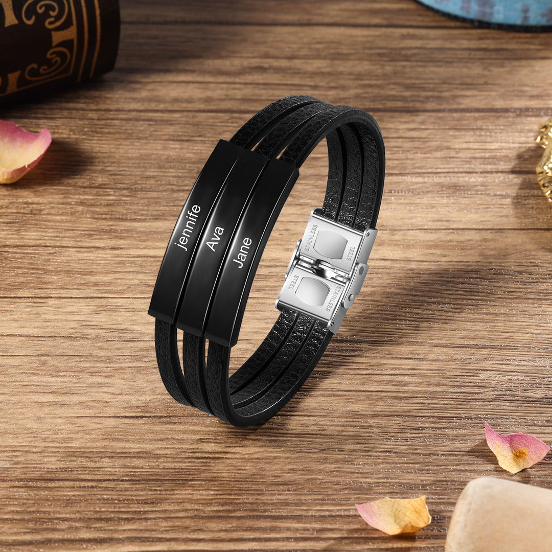 Customizable black leather bracelet with three engravings on a wooden surface.