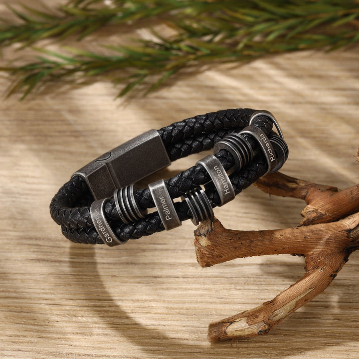 Personalized black braided leather bracelet with dark grey stainless steel rings and custom engravings.