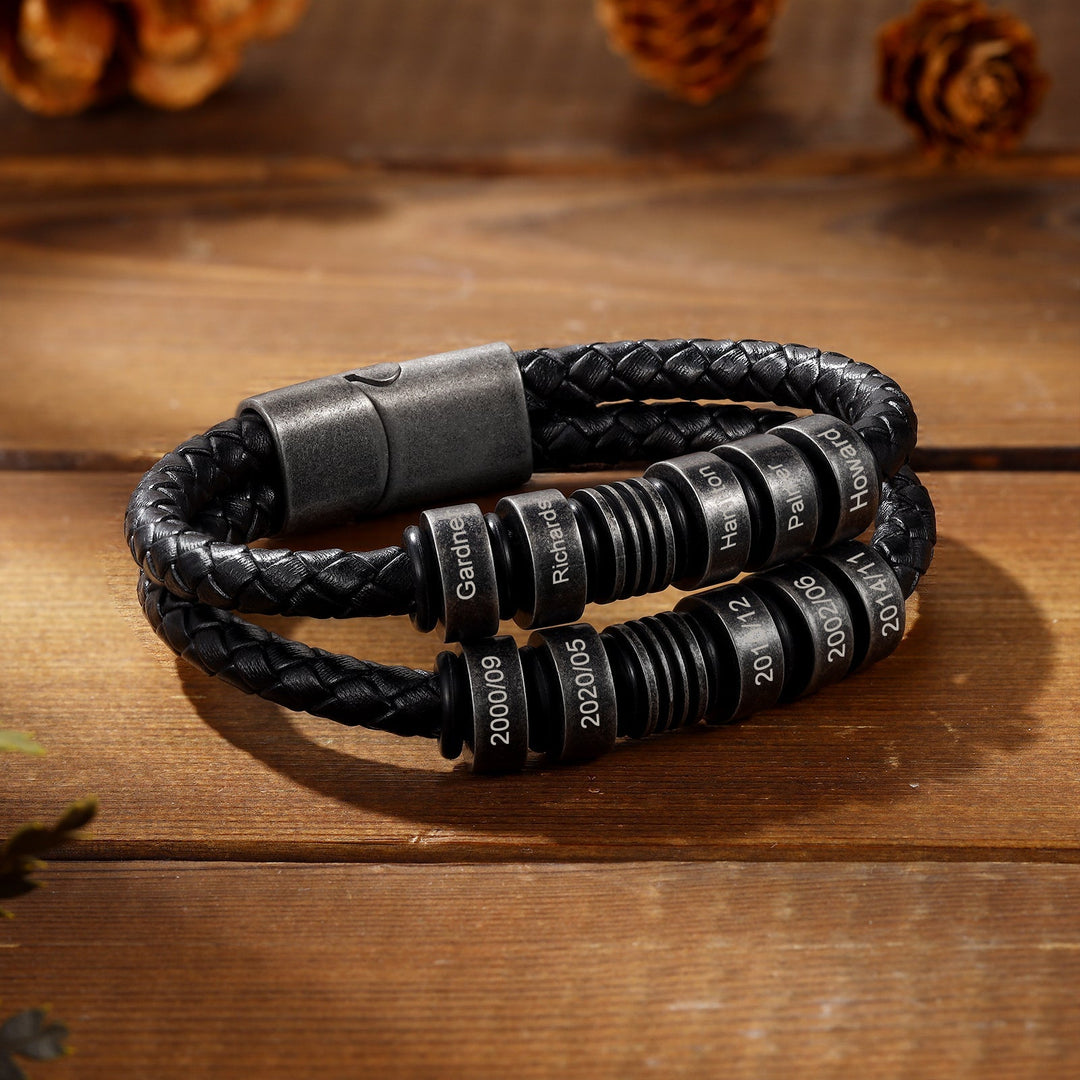 Black braided leather bracelet with personalized engravings on a wooden surface