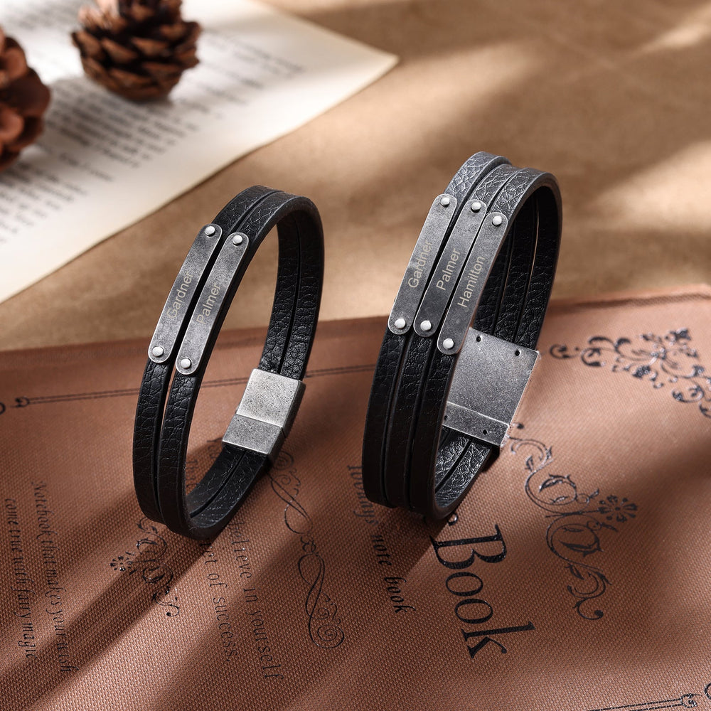 Customizable dark grey leather bracelet with two engravings on a brown decorative surface