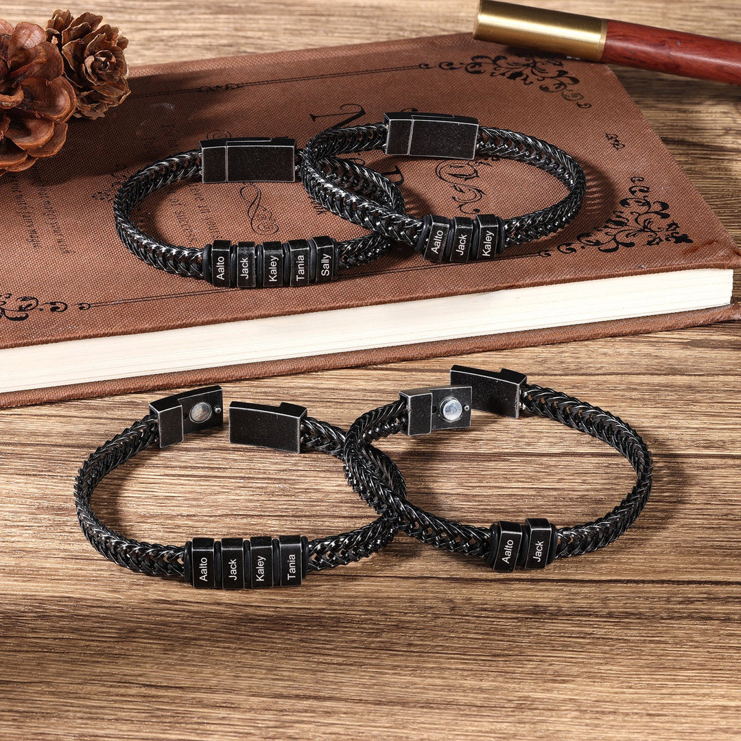 Black vintage-style personalized stainless steel curb chain bracelets with three engravings displayed on wooden surface.