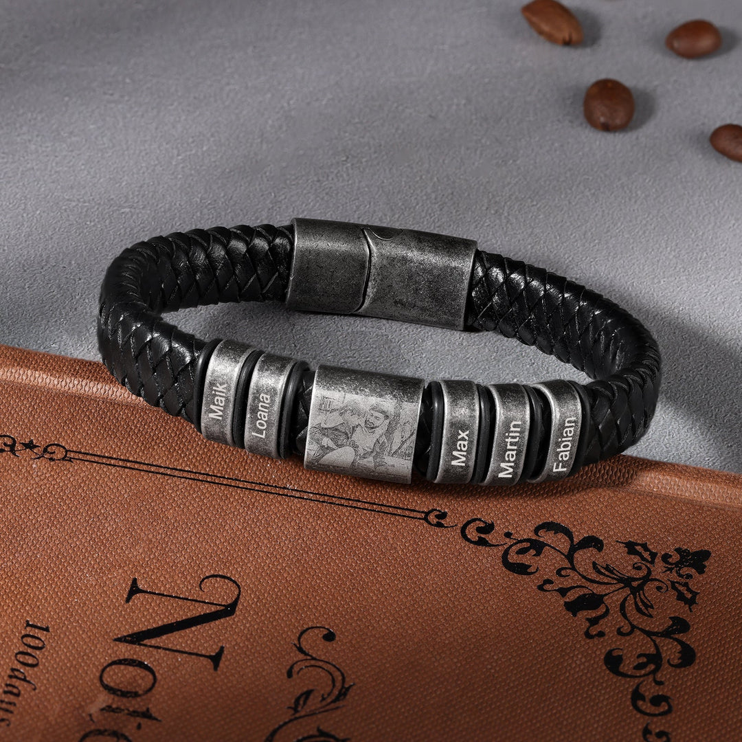 Custom black leather bracelet with three engravings and a photo, stainless steel accents, displayed on vintage book.