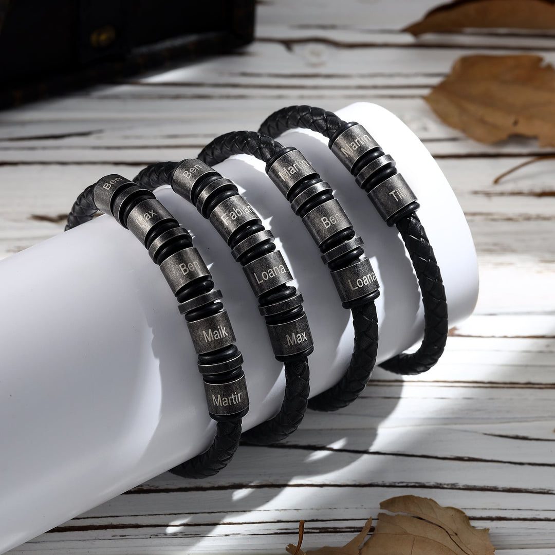 Simple vintage black braided leather bracelet with 2 engraving rings for personalization, displayed on a white surface with autumn leaves.