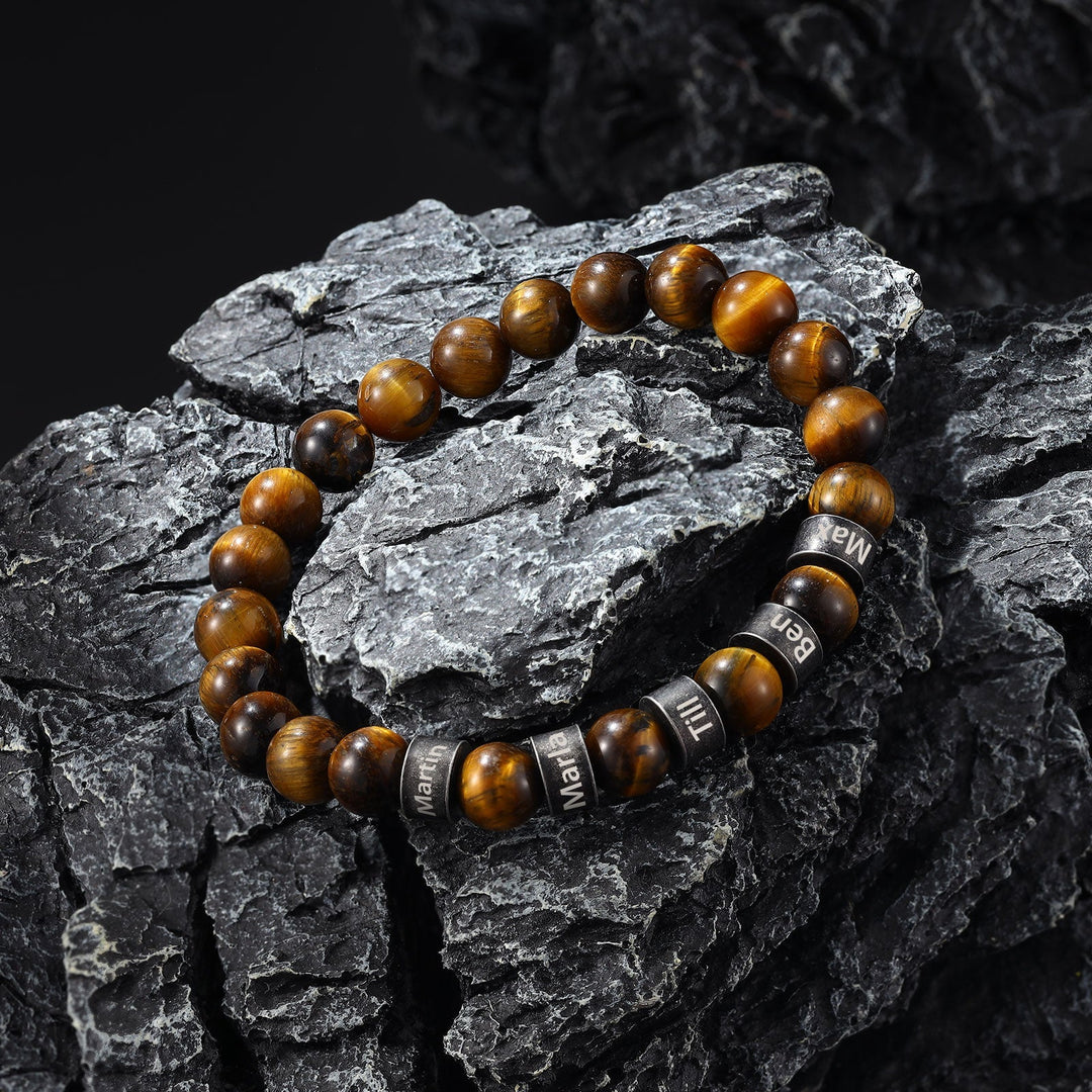 Beautiful light and dark brown beaded bracelet with personalized engraving resting on dark textured stone surface