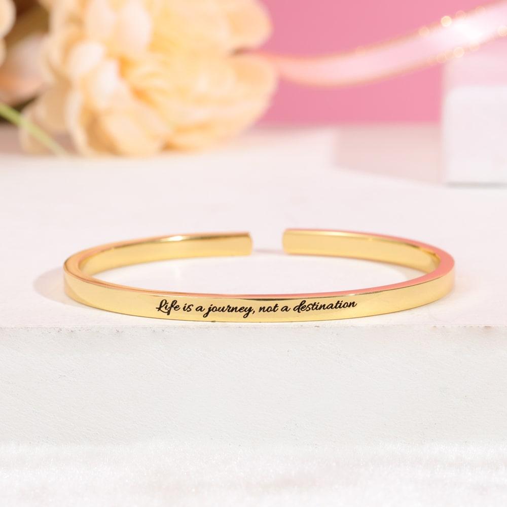 Dual-sided engraved bracelet with "Life is a journey, not a destination" message in gold color.