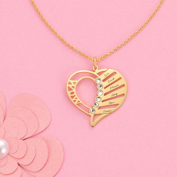 Elegant gold "MOM" heart pendant necklace with personalized birthstones and engravings on a pink background