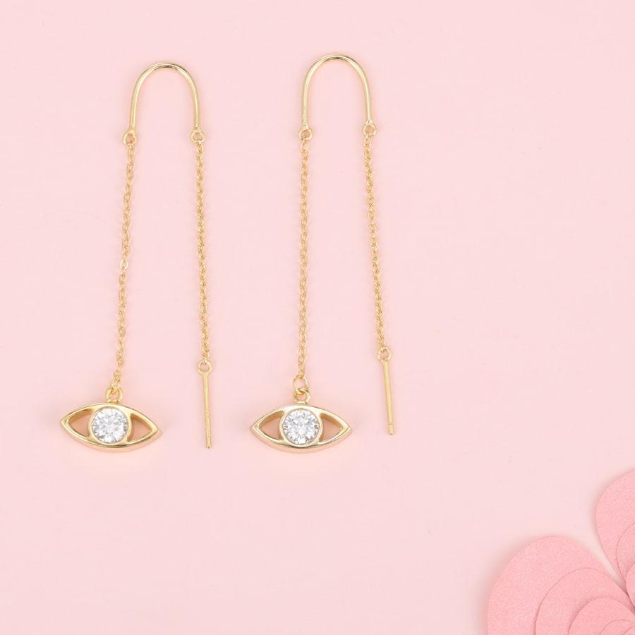 Evil Eye earrings in 925 Sterling Silver with gold finish on a pink background.