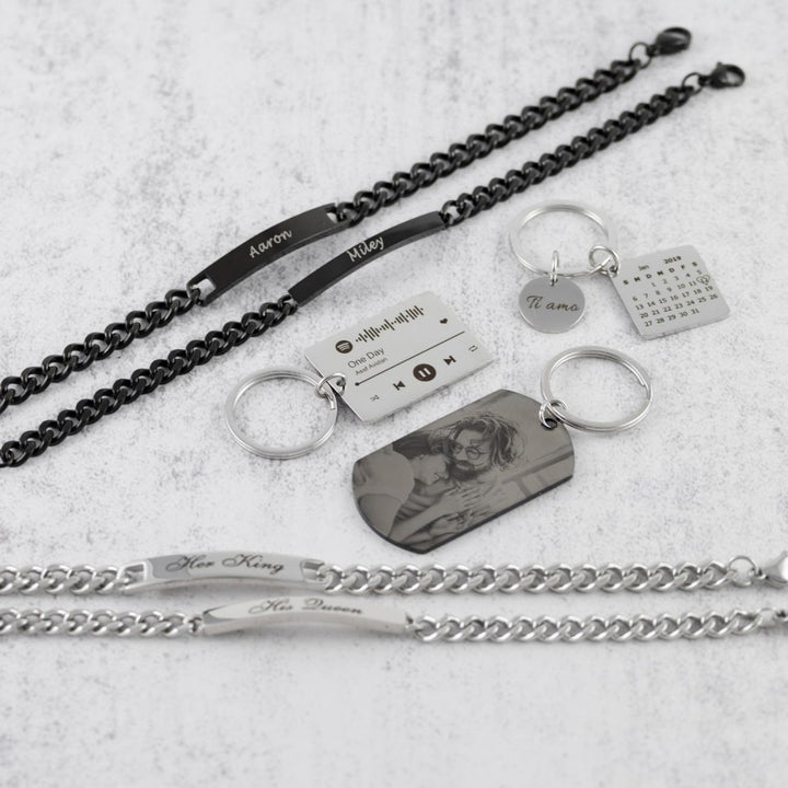 Personalized calendar and engraved keychains with accompanying bracelets in black and silver, displayed on a white surface