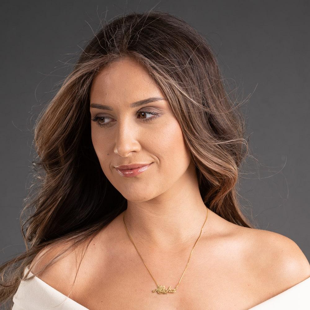 Woman wearing a Bold Cursive Name Necklace in 14 Karat Gold with calligraphy design against a neutral background.