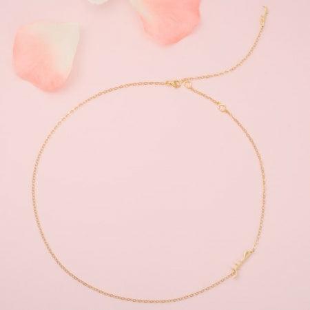 Sabr Hub Arabic Necklace in 14 Karat Gold with a delicate feminine design on a soft pink background