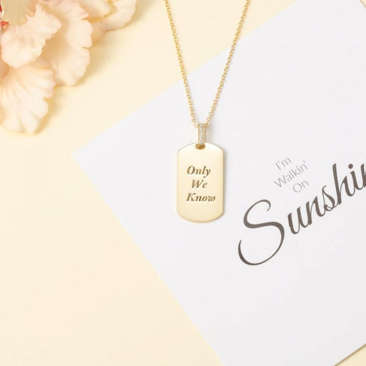 Shiny Radiance Personalized Necklace engraved with "Only We Know" on a gold pendant displayed over a card and floral decoration